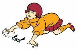 Image description: Picture of cartoon character “Velma” from Scooby Doo, on her knees searching for her glasses sitting right in front of her. She has read hair and is wearing an orange dress.